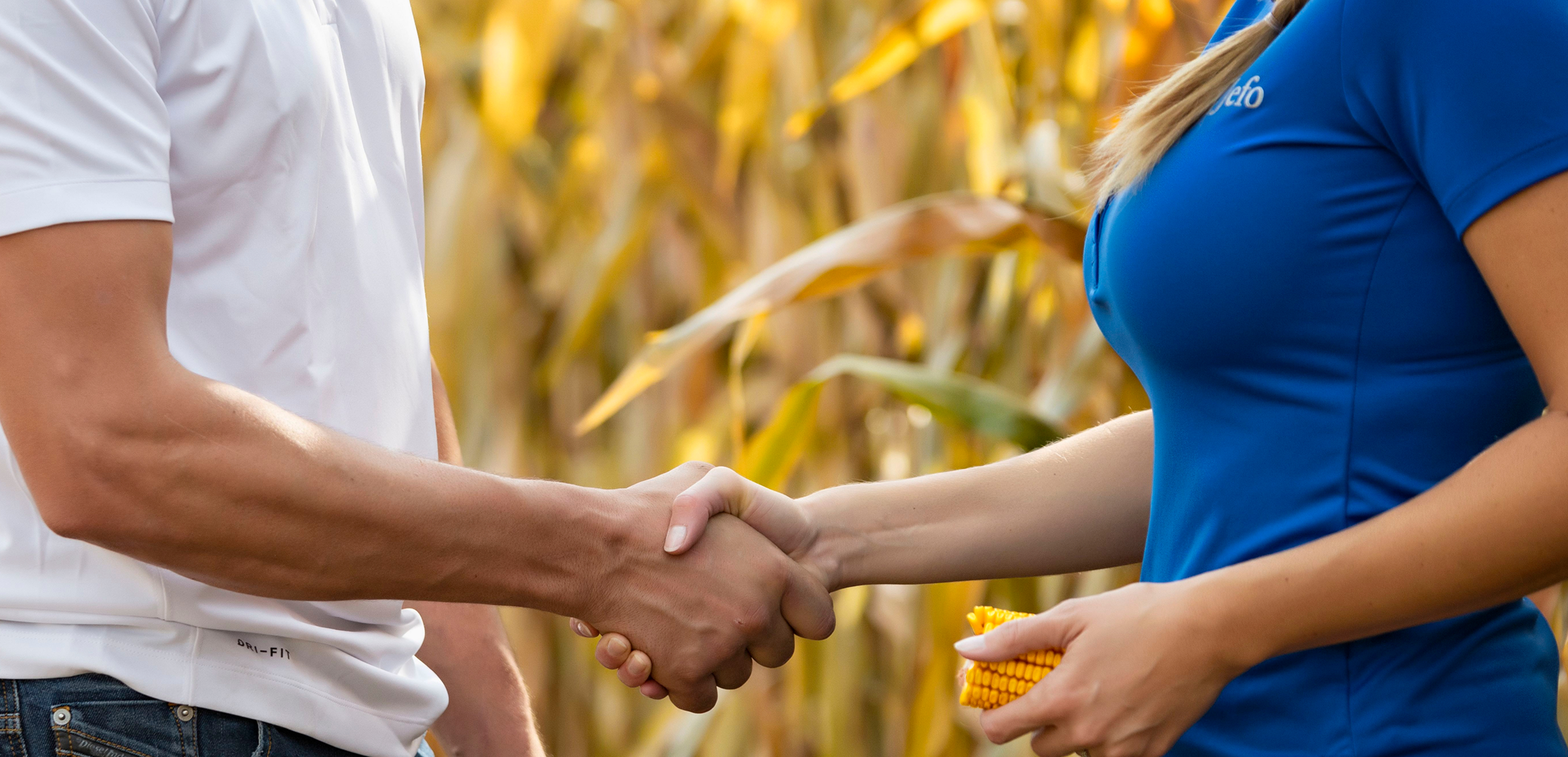 Handshake between a Jefo advisor and a farming client, symbolizing partnership in animal nutrition solutions.