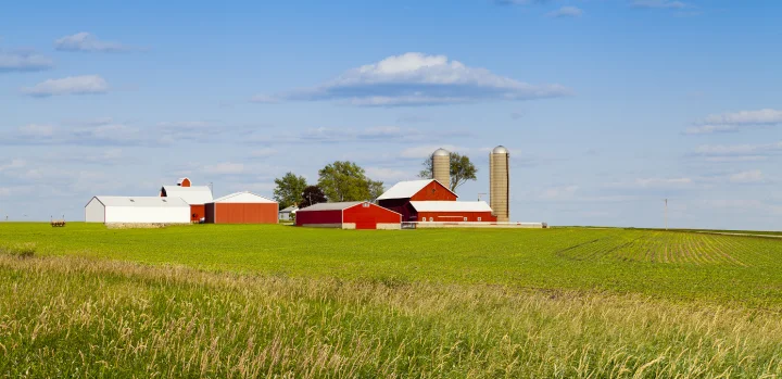 Modern poultry farm surrounded by green fields, representing sustainable production in animal nutrition.