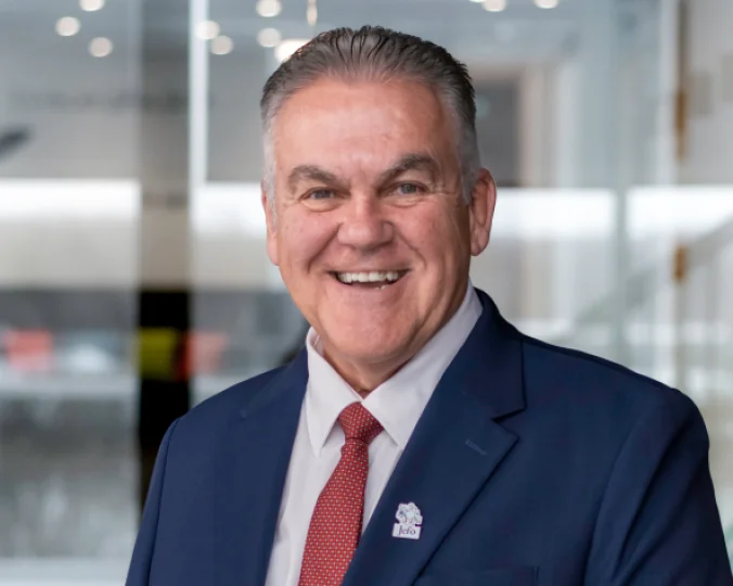 Headshot of Jean Fontaine with a blue suit, a red tie and a Jefo pin.