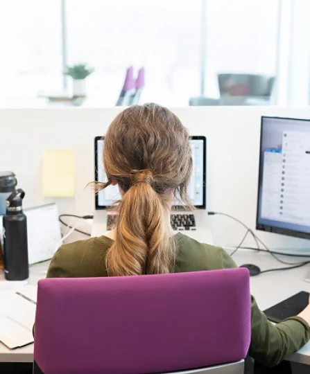Focused employee at workstation with dual screens, representing expert support in animal nutrition.