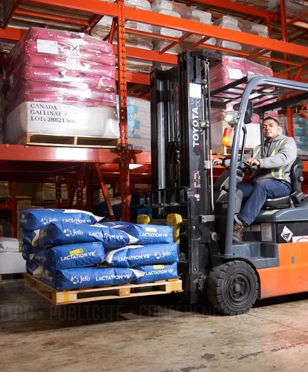 Employee operating a forklift at Jefo’s warehouse, handling Lactation VB animal nutrition ingredient bags.